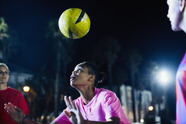 Junge Fußballspielerin köpft den Ball auf dem Feld bei Nacht - CAIF20106