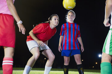 Young female soccer players practicing on field at night, heading the ball - CAIF20111