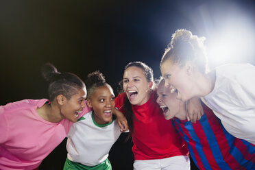 Enthusiastic young female soccer teammates celebrating, cheering in huddle - CAIF20118