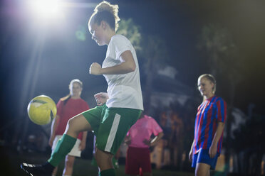 Junge Fußballspielerin, die den Ball kickt und nachts auf dem Feld übt - CAIF20119