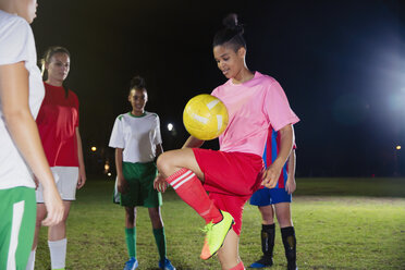 Junge Fußballspielerin beim Üben, Ball auf dem Knie auf dem nächtlichen Spielfeld aufprallen lassen - CAIF20121