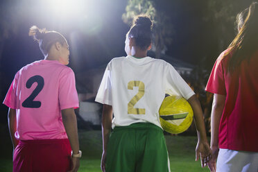 Junge Fußballspielerinnen mit Ball unterhalten sich nachts auf dem Feld - CAIF20122