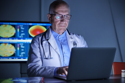 Fokussierter männlicher Chirurg bei der Arbeit am Laptop im Krankenhaus - CAIF20167
