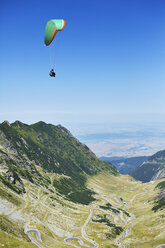 Mann beim Gleitschirmfliegen über den Bergen - CAVF17795