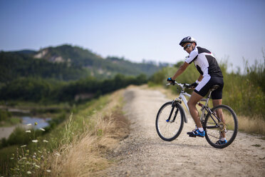 Portrait of cyclist with bicycle on dirt road - CAVF17820