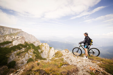 Seitenansicht eines Mannes mit Fahrrad auf einem Berg gegen den Himmel - CAVF17840