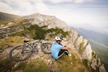 Blick von oben auf einen Mann, der mit dem Fahrrad auf einem Berg sitzt - CAVF17841