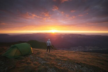 Rear view of man standing on mountain during sunset - CAVF17861