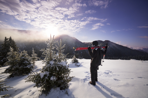 Rear view of skier on snowy mountain against sky stock photo