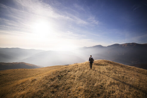 Rückansicht eines männlichen Rucksacktouristen, der auf einem Berg gegen den Himmel läuft - CAVF17919