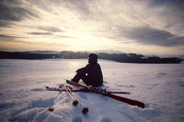 Rückansicht eines Skifahrers, der auf einem verschneiten Berg gegen den Himmel sitzt - CAVF17924