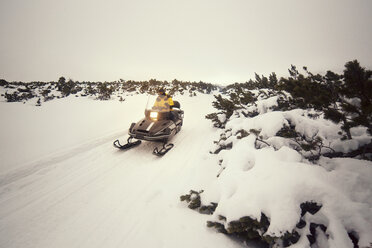 Mann fährt Motorschlitten auf verschneitem Feld gegen den Himmel - CAVF17930