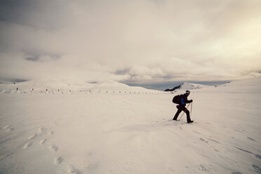 Seitenansicht von Skifahrer zu Fuß auf Schnee gegen bewölkten Himmel - CAVF17931