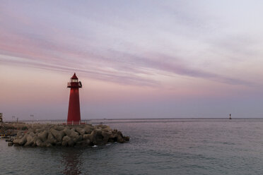 Roter Leuchtturm auf dem Pier am Meer gegen den Himmel in der Abenddämmerung - CAVF17963
