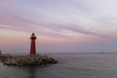 Red lighthouse on pier by sea against sky during dusk - CAVF17963