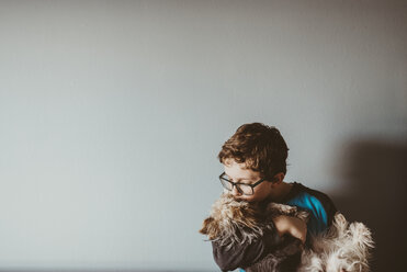 Junge küsst Yorkshire Terrier zu Hause an der Wand - CAVF18023