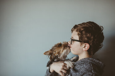 Yorkshire Terrier leckt zu Hause das Gesicht eines Jungen gegen die Wand - CAVF18025