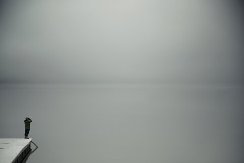 Mann steht am Meer vor bewölktem Himmel bei nebligem Wetter - CAVF18050
