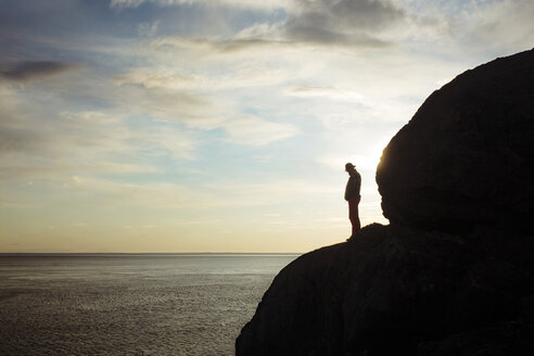 Silhouette Mann stehend auf felsigem Berg am Meer gegen den Himmel - CAVF18060