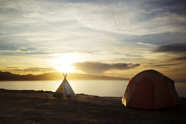 Tents and surfboards on sand against sea during sunset - CAVF18080