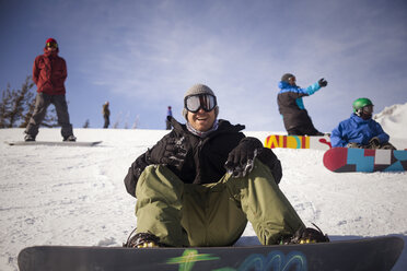 Fröhliche Freunde beim Snowboarden auf verschneitem Feld gegen den Himmel - CAVF18083
