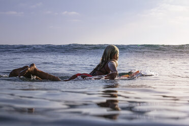 Frau schwimmt auf Surfbrett im Meer gegen den Himmel - CAVF18089