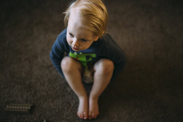 Hoher Blickwinkel auf einen Jungen, der zu Hause auf dem Boden sitzt - CAVF18125