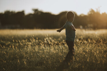 Side view of boy playing on grassy field - CAVF18135