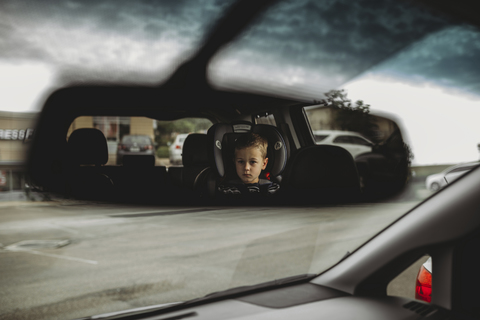 Reflexion eines Jungen im Rückspiegel eines Autos, lizenzfreies Stockfoto