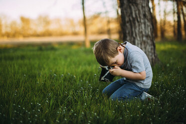 Side view of boy photographing through vintage camera - CAVF18143