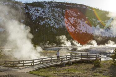 Mitteldistanz eines Wanderers mit Blick auf Dampf, der aus einer heißen Quelle im Yellowstone National Park austritt - CAVF18193