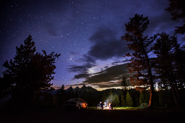 Camping amidst trees in forest against starry sky at night - CAVF18195