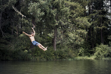 Man diving into lake by trees at forest - CAVF18210