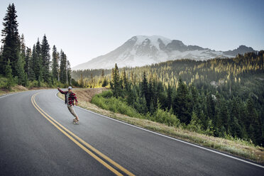 Junger Mann fährt Skateboard auf der Straße gegen den Himmel am Mt. Rainier National Park - CAVF18224