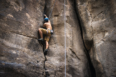 Low angle view of man rock climbing on sunny day - CAVF18236