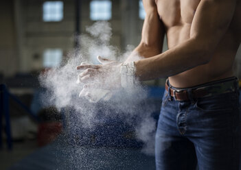 Midsection of male gymnast applying chalk powder on hands - CAVF18248