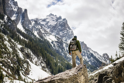 Rückansicht eines Wanderers, der auf einem Felsen vor einem schneebedeckten Berg steht - CAVF18279
