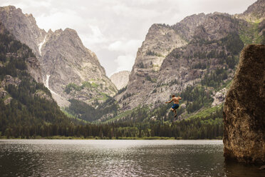 Mann taucht im Grand Teton National Park gegen den Himmel in einen See - CAVF18288