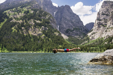 Teenager diving into lake by mountains - CAVF18291