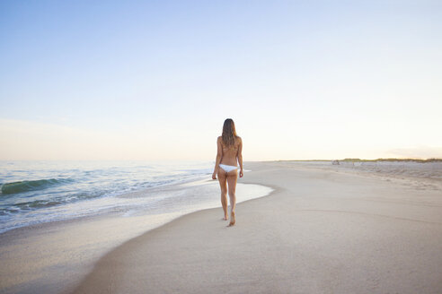 Rückansicht einer Frau, die am Strand gegen den klaren Himmel läuft - CAVF18334