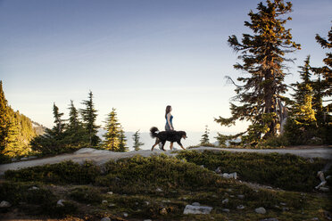 Seitenansicht einer Frau, die mit ihrem Hund auf einem Berg spazieren geht - CAVF18360