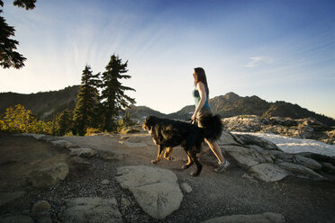 Side view woman walking with dog on mountain - CAVF18362