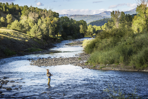 Mann beim Angeln im Fluss inmitten von Akten, lizenzfreies Stockfoto