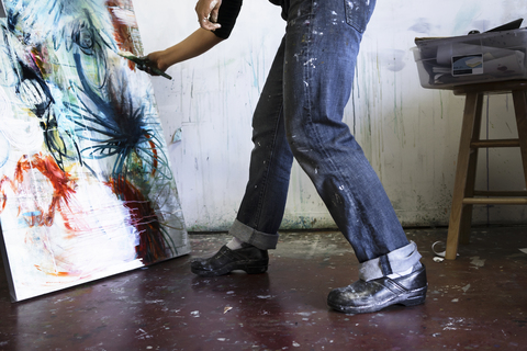 Niedriger Ausschnitt einer Frau, die in einem Kunstatelier auf Leinwand malt, lizenzfreies Stockfoto