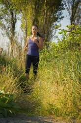 Woman jogging on field in forest - CAVF18421