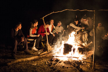 Freunde sitzen nachts am Lagerfeuer - CAVF18477
