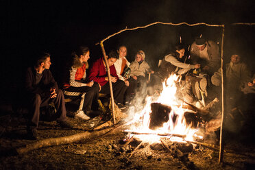 Friends sitting near campfire at night - CAVF18477