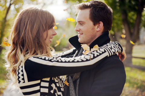 Romantisches Paar, das lächelnd im Park steht, lizenzfreies Stockfoto