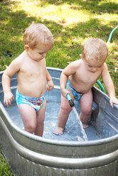 Baby girls playing in washtub at lawn - CAVF18618