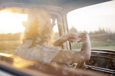 Rückansicht einer Frau am Steuer eines Autos an einem sonnigen Tag - CAVF18679